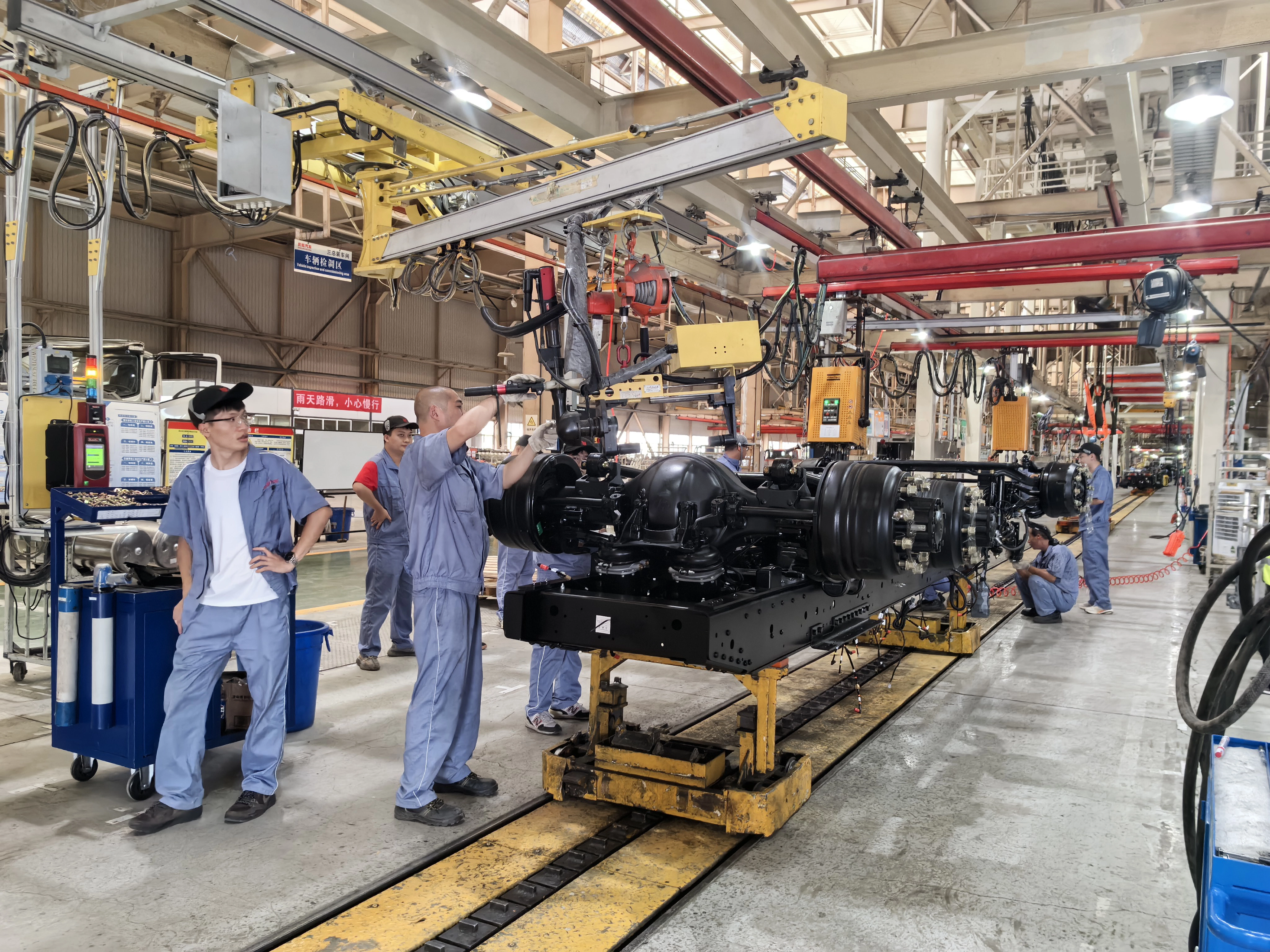 Technicians performing trial assembly on the EVC61 chassis and axle assembly on the factory line